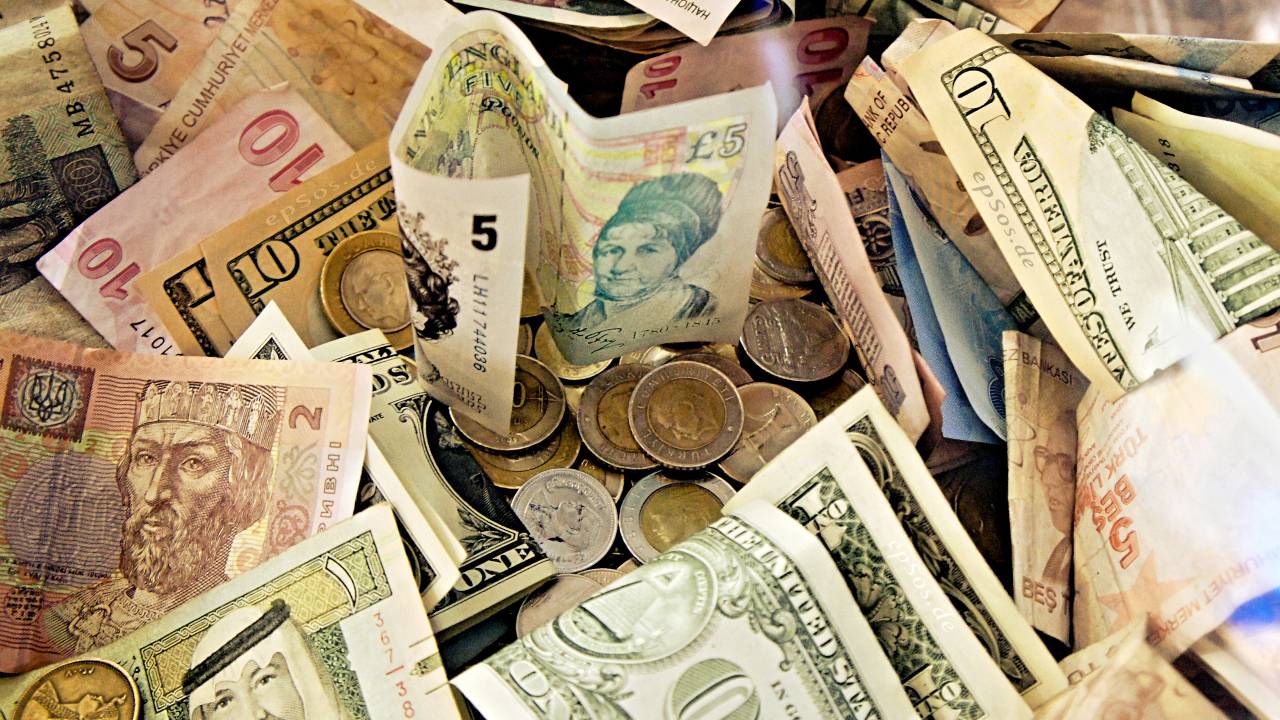 Moedas e cédulas de vários países dispostas de forma desorganizada