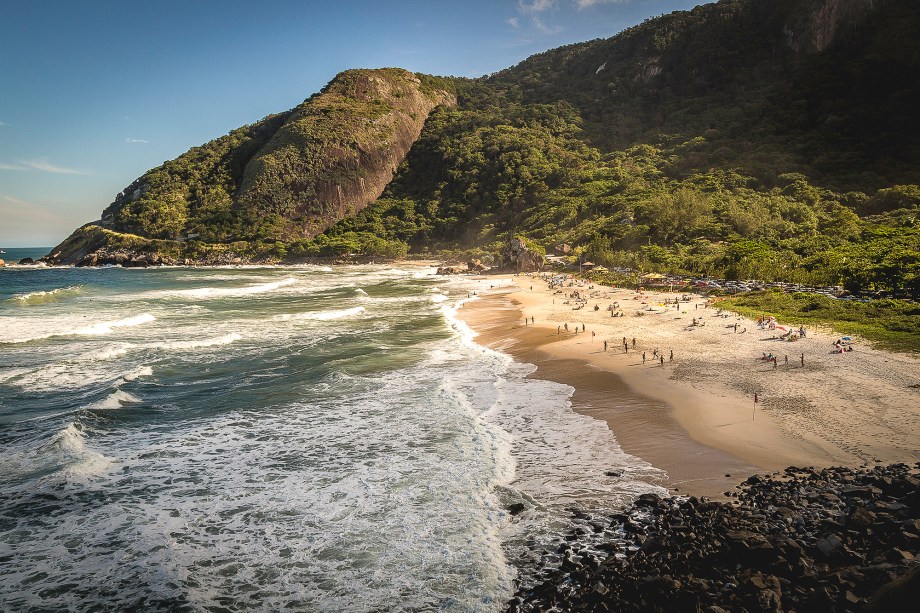 A chegada às duas mais belas praias do litoral carioca (Prainha e <a href="https://viajeaqui.abril.com.br/estabelecimentos/br-rj-rio-de-janeiro-atracao-praia-de-grumari" target="_blank">Grumari</a>, mais à frente) já impressiona: serpenteando pela estrada, numa das curvas, avista-se o mar verde da Prainha, cercado por morros e areia fofa. Com estrutura organizada de estacionamento, ducha e quiosque, é só curtir o visual e beliscar alguma porção por ali mesmo.