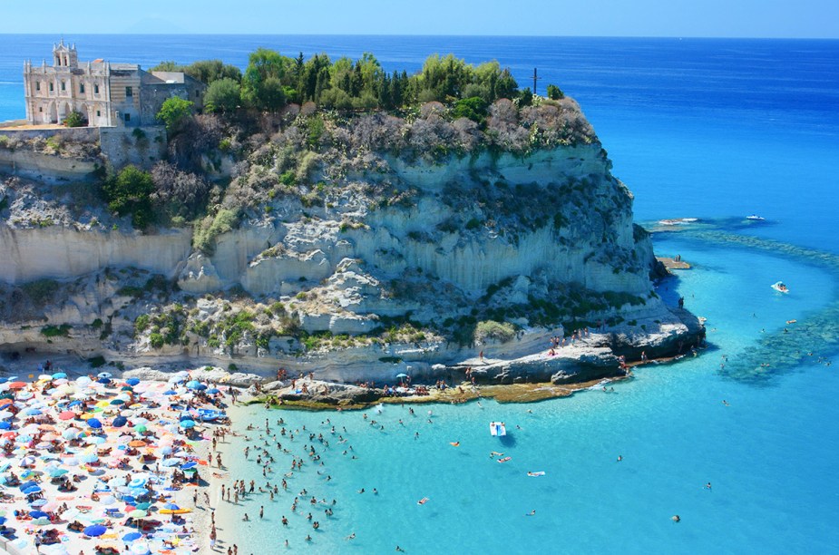 <strong>Praia de Tropea</strong> Diz a lenda que foi Hércules quem fundou a cidade de Tropea, mas a principal história é que a cidade é ocupada desde os tempos neolíticos. Hoje, a deslumbrante Praia de Tropea é o que atrais milhares de turistas todos os anos, mais italianos do que estrangeiros. A cidade fica sobre um precipício, o que favorece a vista do pôr do sol e proporciona fotos quase “aéreas”. <a href="https://www.booking.com/searchresults.en-gb.html?aid=332455&lang=en-gb&sid=eedbe6de09e709d664615ac6f1b39a5d&sb=1&src=searchresults&src_elem=sb&error_url=https%3A%2F%2Fwww.booking.com%2Fsearchresults.en-gb.html%3Faid%3D332455%3Bsid%3Deedbe6de09e709d664615ac6f1b39a5d%3Bcity%3D-128948%3Bclass_interval%3D1%3Bdest_id%3D-128764%3Bdest_type%3Dcity%3Bdtdisc%3D0%3Bfrom_sf%3D1%3Bgroup_adults%3D2%3Bgroup_children%3D0%3Binac%3D0%3Bindex_postcard%3D0%3Blabel_click%3Dundef%3Bno_rooms%3D1%3Boffset%3D0%3Bpostcard%3D0%3Braw_dest_type%3Dcity%3Broom1%3DA%252CA%3Bsb_price_type%3Dtotal%3Bsearch_selected%3D1%3Bsrc%3Dsearchresults%3Bsrc_elem%3Dsb%3Bss%3DSan%2520Teodoro%252C%2520%25E2%2580%258BSardinia%252C%2520%25E2%2580%258BItaly%3Bss_all%3D0%3Bss_raw%3DSan%2520Teodoro%3Bssb%3Dempty%3Bsshis%3D0%3Bssne_untouched%3DSan%2520Vito%2520lo%2520Capo%26%3B&ss=Tropea%2C+%E2%80%8BCalabria%2C+%E2%80%8BItaly&ssne=San+Teodoro&ssne_untouched=San+Teodoro&city=-128764&checkin_monthday=&checkin_month=&checkin_year=&checkout_monthday=&checkout_month=&checkout_year=&no_rooms=1&group_adults=2&group_children=0&highlighted_hotels=&from_sf=1&ss_raw=Tropea+&ac_position=0&ac_langcode=en&dest_id=-131408&dest_type=city&place_id_lat=38.678001&place_id_lon=15.8973&search_pageview_id=e9d690fb446e02a7&search_selected=true&search_pageview_id=e9d690fb446e02a7&ac_suggestion_list_length=5&ac_suggestion_theme_list_length=0" target="_blank" rel="noopener"><em>Busque hospedagens em Tropea no Booking.com</em></a>