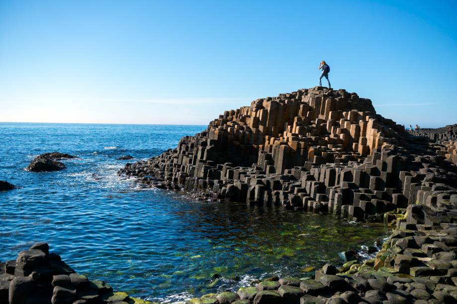 <strong>Calçada dos Gigantes, <a href="https://viajeaqui.abril.com.br/paises/irlanda" rel="Irlanda" target="_blank">Irlanda</a></strong>De acordo com a lenda, esse lugar teria sido construído por um gigante com a intenção de conectar a Irlanda à <a href="https://viajeaqui.abril.com.br/paises/escocia" rel="Escócia" target="_blank">Escócia</a> através de uma calçada, porque ele não cabia dentro de nenhum barco. Voltando para o mundo real, essas 40 mil rochas prismáticas de basalto são produto de uma erupção vulcânica que ocorreu há 60 mil anos. O calor de 1000ºC teria derretido as pedras, fazendo com que elas passassem por fendas no solo e, quando saíram e entraram em contato com o ar, rapidamente esfriaram e se solidificaram nesse formato