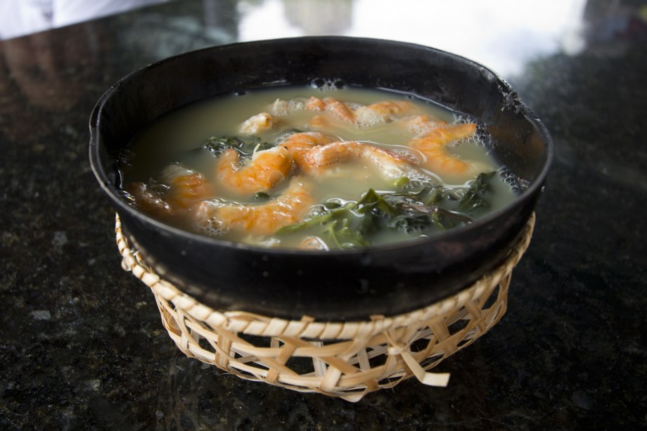 Esta sopa tem um caldo feito com <a href="https://viajeaqui.abril.com.br/materias/ingredientes-da-culinaria-da-amazonia?foto=9#9" rel="tucupi" target="_blank">tucupi</a> (molho feito de mandioca brava) e goma (farinha de tapioca), para quebrar a acidez. As folhas de <a href="https://viajeaqui.abril.com.br/materias/ingredientes-da-culinaria-da-amazonia?foto=2#2" rel="jambu" target="_blank">jambu</a> dão um toque especial, pois anestesia levemente a boca. Para completar a receita, não podem faltar os camarões salgados. O<strong> tacacá </strong>mais famoso, <a href="https://viajeaqui.abril.com.br/estabelecimentos/br-am-manaus-restaurante-tacaca-da-gisela" rel="da Gisela" target="_blank">da Gisela</a>, é vendido em uma barraca na frente do Teatro Amazonas, no Centro de Manaus.