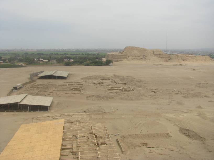 Vista a partir da Huaca de la Luna: vestígios de ruas, avenidas, casas e praças que formavam a cidade dos moches, com a Huaca del Sol ao fundo (atrás os campos de cana de açúcar que cercam Trujillo)