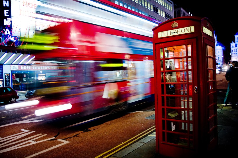 O icônico Routemaster, ónibus vermelho de dois andares, passando atrás de outro símbolo londrino: as cabines telefônicas vermelhas!