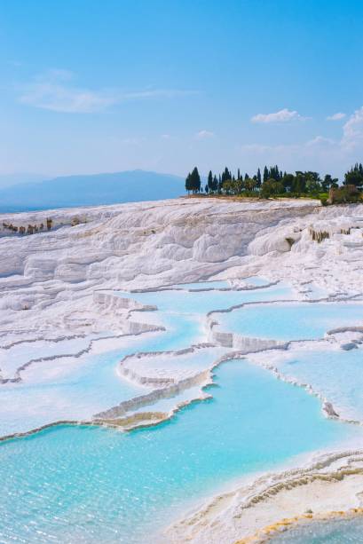 <strong>Pamukkale, <a href="https://viajeaqui.abril.com.br/paises/turquia" rel="Turquia" target="_blank">Turquia</a></strong>                Parece gelo, mas é pedra! Em turco, a palavra “pamukkale” significa “castelo de algodão” e realmente não há melhor jeito de descrever esta paisagem quase idílica da Turquia. O lugar é constituído por uma série de piscinas termais, as quais chegam até 200 metros de altura, e que são preenchidas por águas em tons bem claros de azul. O efeito cascata é causado pelo calor que irradia de baixo do monte e derrete as pedras calcárias, que são depois solidificadas novamente
