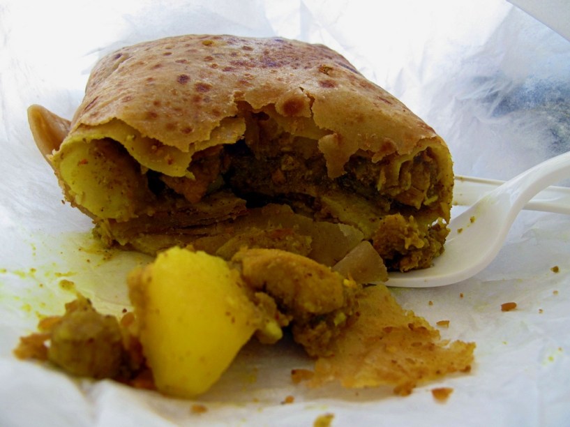 <strong>Chicken Roti, Trinidad e Tobago</strong><br /><em>Roti</em>? Mas isso não é um prato indiano? Sim, caros, num pequeno e próspero arquipélago grudado na costa venezuelana vive um povo que é uma doida mistura de negros, britânicos e indianos. Estes últimos são mais de 40% da população e trouxeram para o país parte de sua cultura e, é claro, gastronomia.O mais simbólico produto deste movimento é uma massaroca de frango com curry, envelopada numa fina folha de pão, o <em>roti</em>. Você encontrará a condimentada iguaria em disputadas lojinhas espalhadas por todo o país. 