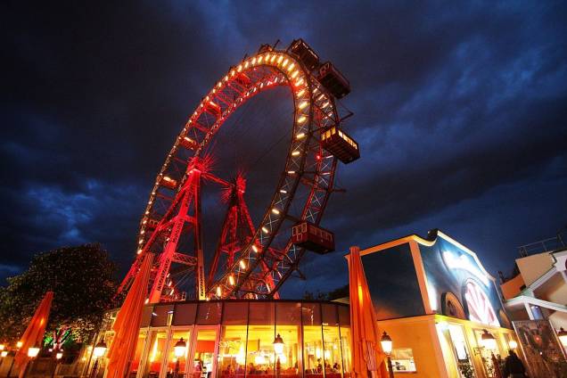 Wiener Riesenrad significa literalmente “roda-gigante vienense”. Foi construída em 1897 no parque de diversões Wurstelprater de <a href="https://viajeaqui.abril.com.br/cidades/austria-viena" target="_self">Viena</a>, na Áustria, e por mais de 60 anos levou o título de maior do mundo. Hoje não parece tão imponente, nem chega a 65 metros de altura, mas é uma sobrevivente: em 1916 autorizaram a sua demolição, mas faltaram fundos para fazer o serviço e decidiram mantê-la ali, sem incomodar ninguém. Com a chegada da Segunda Guerra Mundial, sofreu danos – das 30 gôndolas originais, só sobraram 15. Mas continua como sempre, firme e forte, sendo um dos principais atrativos turísticos da região Wiener Riesenrad significa literalmente “roda-gigante vienense”. Foi construída em 1897 no parque de diversões Wurstelprater de <a href="https://viajeaqui.abril.com.br/cidades/austria-viena" target="_self">Viena</a>, na Áustria, e por mais de 60 anos levou o título de maior do mundo. Hoje não parece tão imponente, nem chega a 65 metros de altura, mas é uma sobrevivente: em 1916 autorizaram a sua demolição, mas faltaram fundos para fazer o serviço e decidiram mantê-la ali, sem incomodar ninguém. Com a chegada da Segunda Guerra Mundial, sofreu danos – das 30 gôndolas originais, só sobraram 15. Mas continua como sempre, firme e forte, sendo um dos principais atrativos turísticos da região