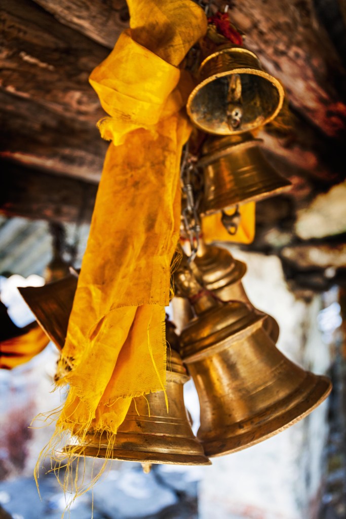 Um molho de sinos ligados por uma corrente e amarrados a um pedaço de tecido, dependuram-se de um teto de madeira