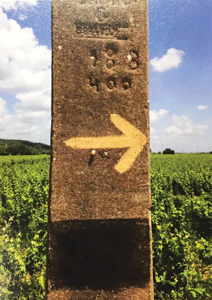 Um poste de pedra marcado à mão com uma seta, que indica o caminho