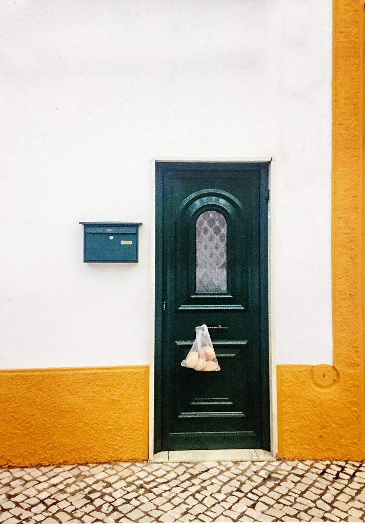 Uma porta solitária em uma parede tem um saco de quatro pães pendurado nela.