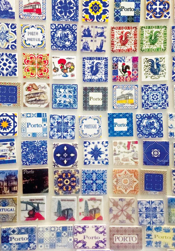 Um mosaico de ímãs com variadas figuras e dizeres. As mais recorrentes são galos e as palavras "Porto" e "Portugal"