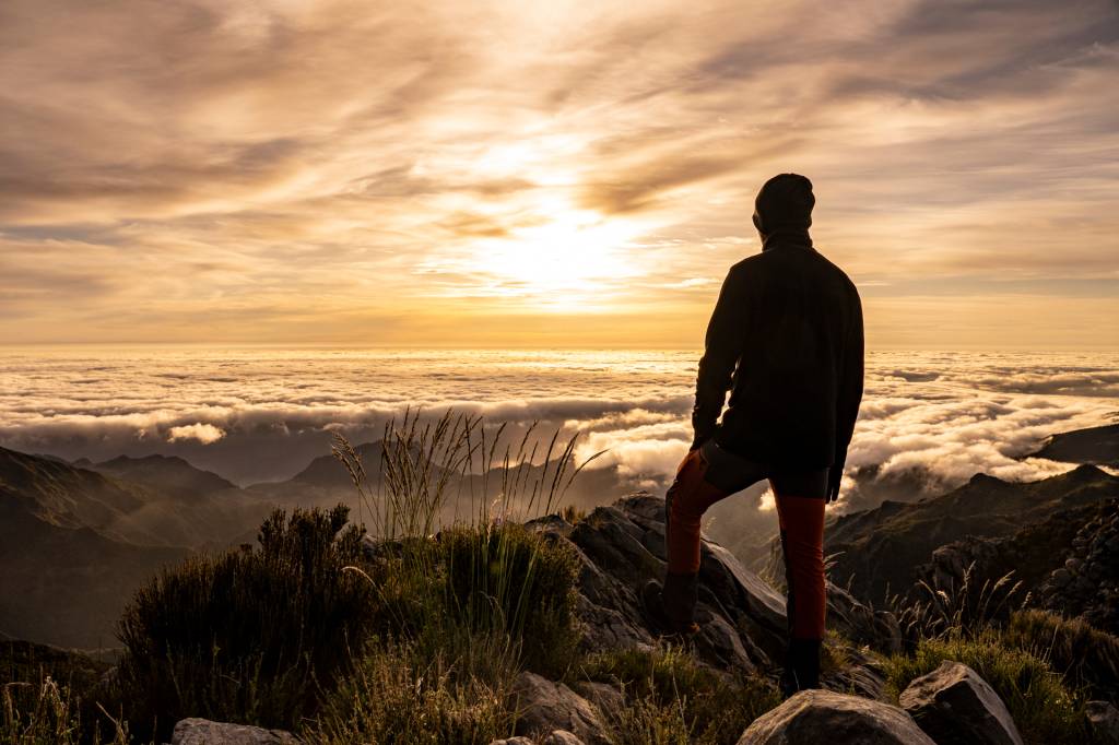 Homem observa o sol nascer acima das nuvens no Pico do Areeiro, na Ilha da Madeira