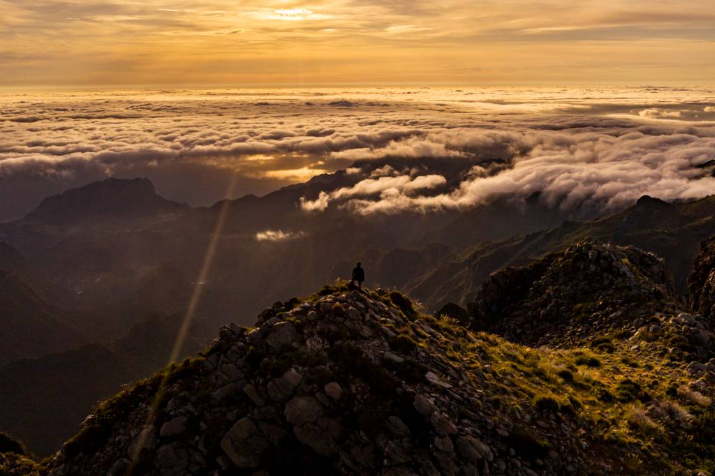 Pessoa sozinha no alto da montanha observa a paisagem acima das nuvens na Ilha da Madeira