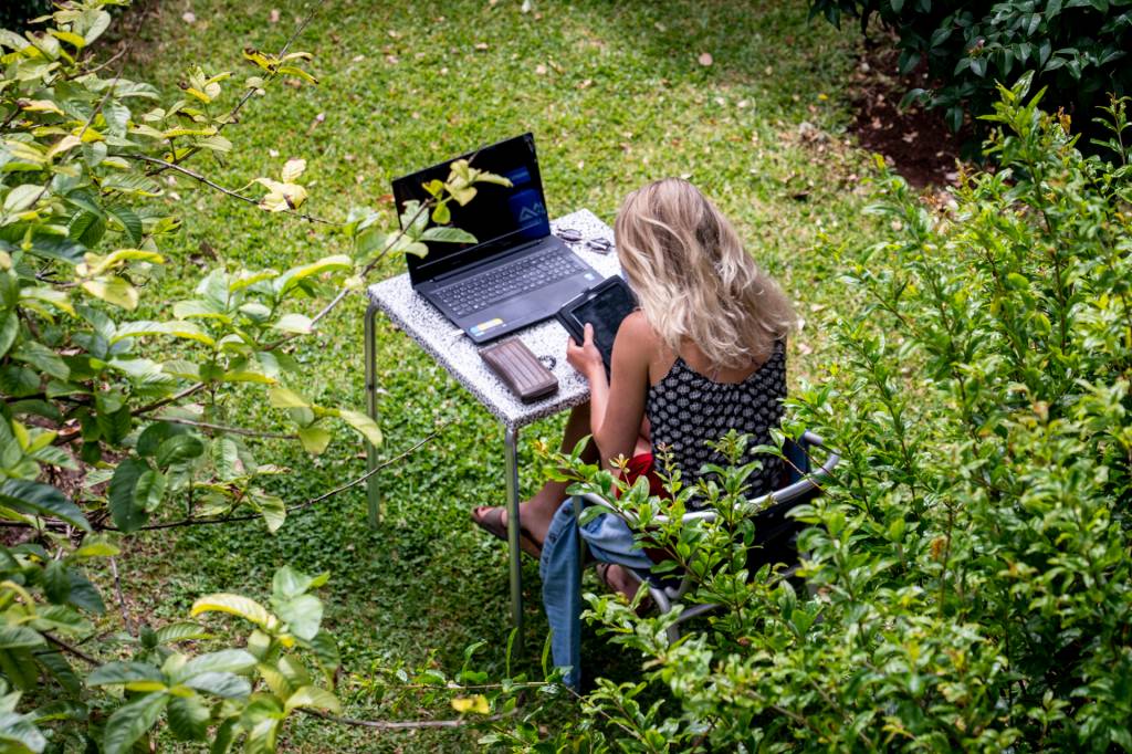 Mulher trabalha no computador em uma mesa no jardim do espaço de co-working da Digital Nomads, na Ilha da Madeira