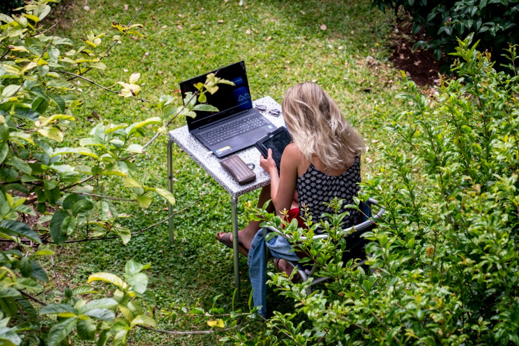 Mulher trabalha no computador em uma mesa no jardim do espaço de co-working da Digital Nomads, na Ilha da Madeira