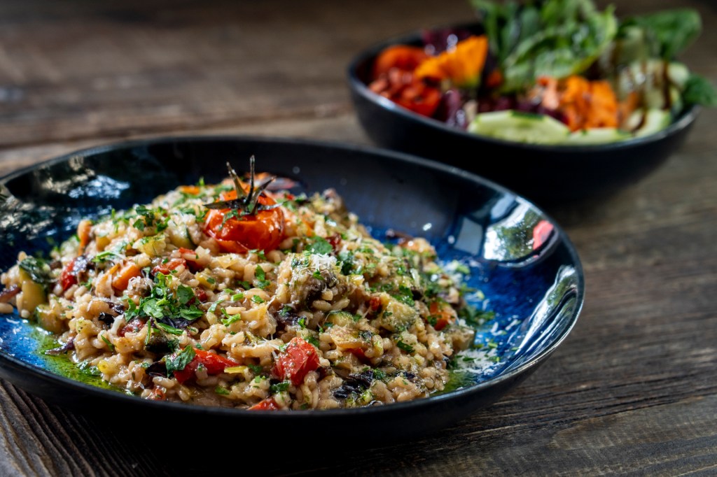 Risoto vegetariano de legumes em um prato azul sobre uma mesa de madeira