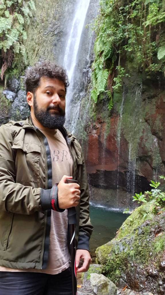 O designer brasileiro João Vicente em frente a uma cachoeira numa trila pela Ilha da Madeira
