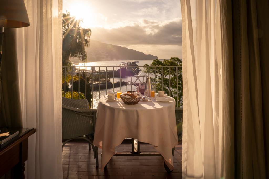 Mesa posta com o café da manhã e duas cadeiras na varanda de um quarto do hotel Reid's Palace, na Ilha da Madeira, com vista do mar
