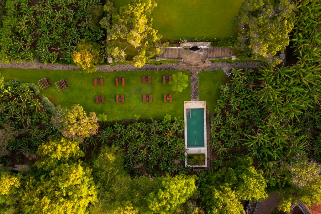 Imagem aérea de um jardim com uma piscina e um gramado com espreguiçadeiras