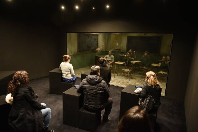 Na instalação" Classroom", os visitantes observam seu reflexo por um vidro que cria uma cena diferente Na instalação" Classroom", os visitantes observam seu reflexo por um vidro que cria uma cena diferente