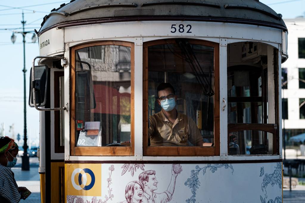 portuguese-gravity-yuEIlTMbGDc-unsplash Elétrico (antigo bonde) com detalhes em madeira em Lisboa, com o motorista usando máscara contra a infecção por covid-19