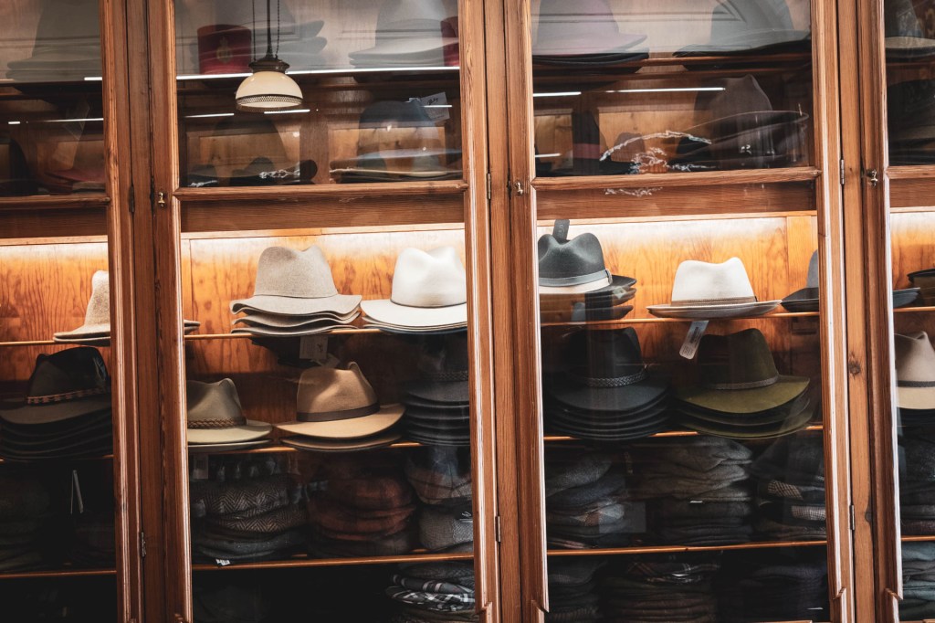 Vitrine de uma loja com uma luz do lado de dentro e dezenas de chapéus