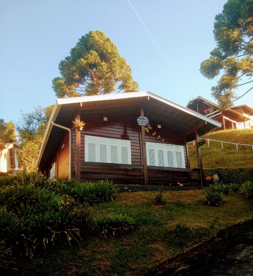 Manacá House, Campos do Jordão, São Paulo A fotografia colorida mostra uma casinha de madeira com portas e detalhas em branco