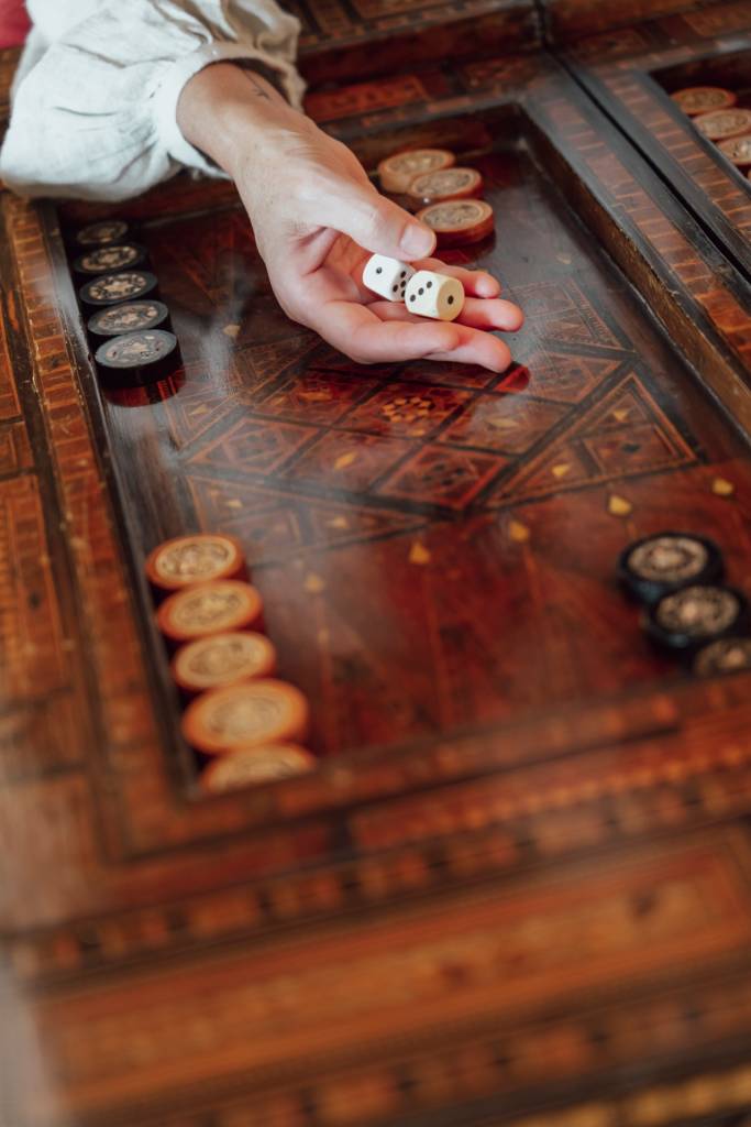 46 Detalhes de uma mão segurando dois dados sobre uma mesa de jogos em madeira