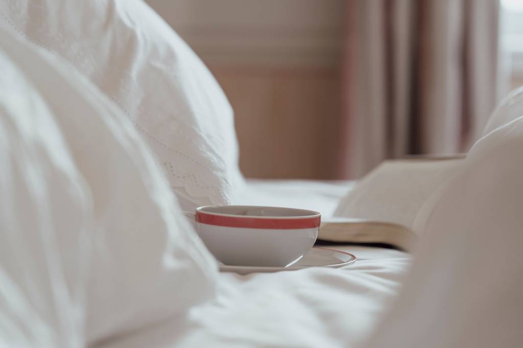 53 Xícara de chá e livro sobre a cama desarrumada