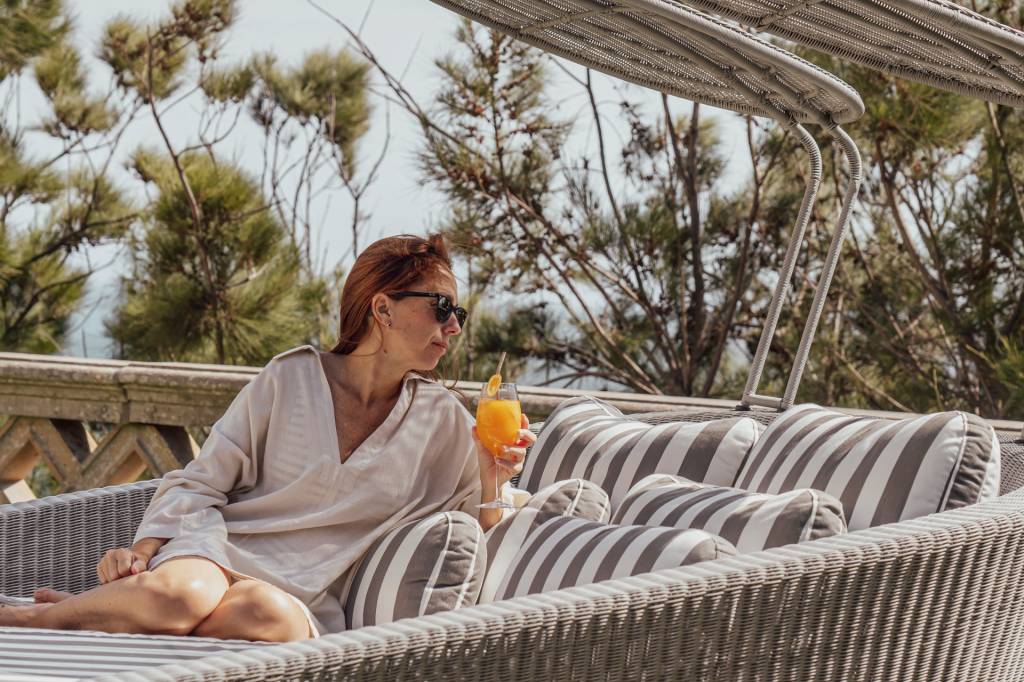 72 Mulher com um copo de suco de laranja na mão, em uma espreguiçadeira