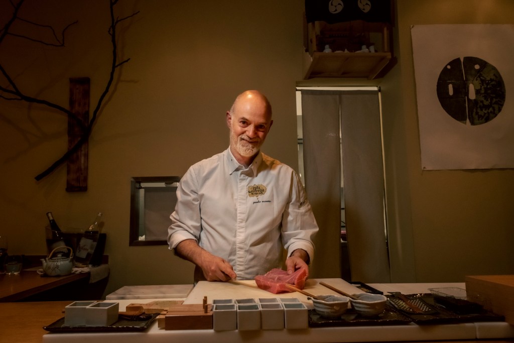 O sushimen Paulo Morais, com uniforma branco de cozinheiro, mostra uma grande peça de atum