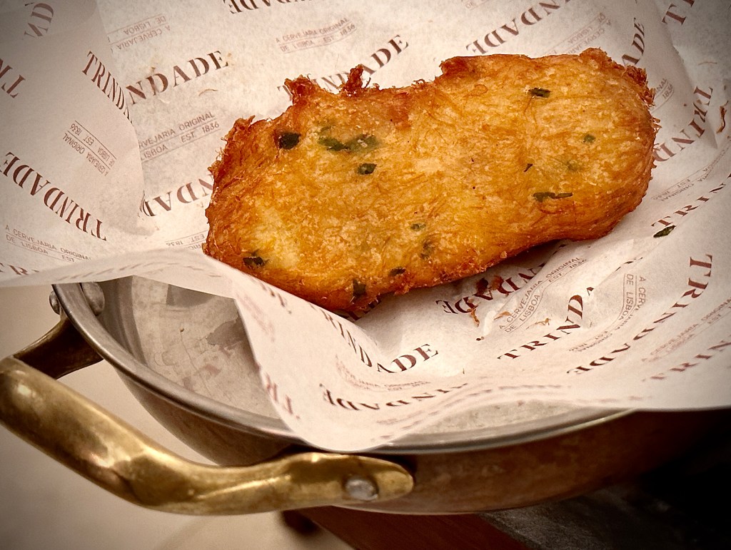 Pequena travessa de cobre com um bolinho de bacalhau, uma das especialidades do restaurante