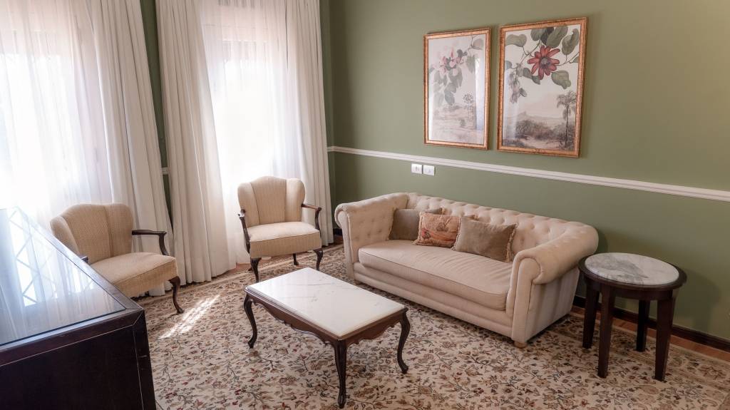 Sala de estar da Suíte Nobre, Grande Hotel Termas de Araxá, Minas Gerais, Brasil A fotografia colorida mostra uma sala de estar com móveis antigos em creme, parede verde e pinturas florais