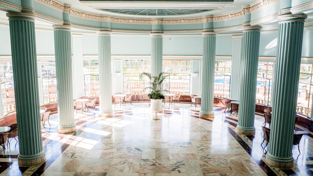 Salão dos Araxás, Grande Hotel Termas de Araxá, Minas Gerais, Brasil A fotografia colorida mostra um salão azul com muitas janelas e colunas com aspecto clássico